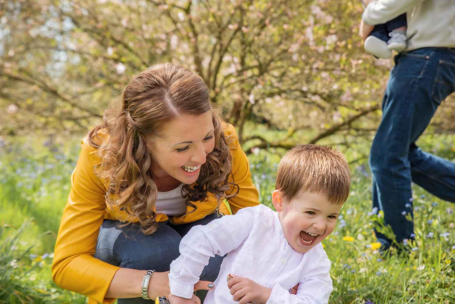 Stunning family portrait of a beautiful family laughing and enjoying themselves, in a background of Spring flowers. Taken at Nymans National Trust Gardens, West Sussex
